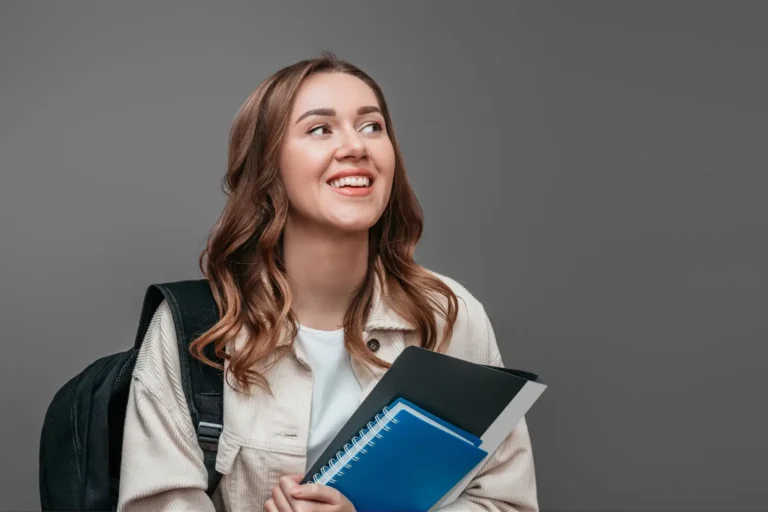 A smiling student holding notebooks, preparing for the IELTS exam and understanding the IELTS scoring system