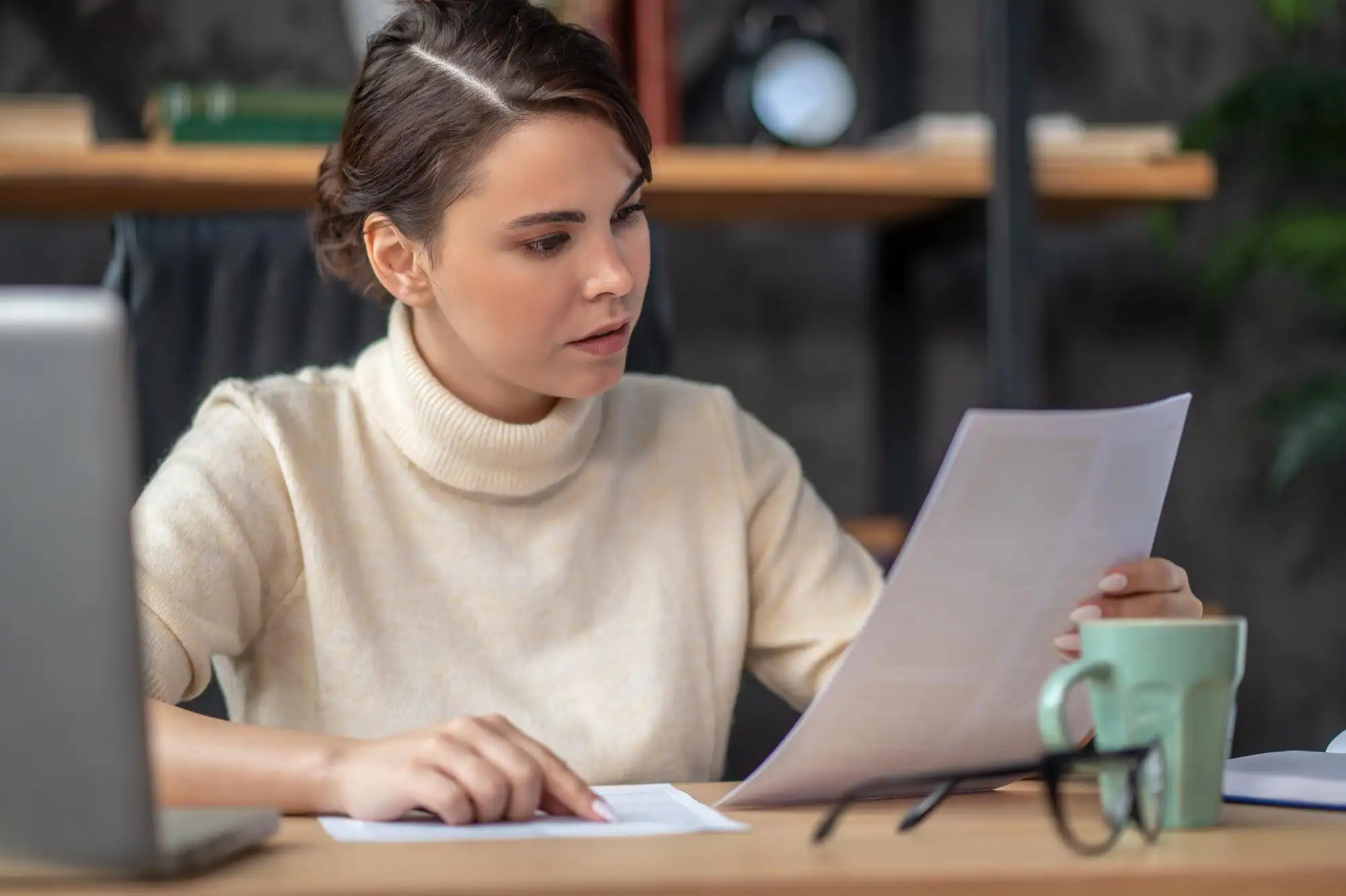 Woman reviewing documents at her desk, planning to reschedule or cancel IELTS test